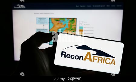 Stuttgart, 28.10.2023: Person mit Handy mit Logo der Firma Reconnaissance Energy Africa Ltd. (ReconAfrica) vor der Webseite. Stockfoto