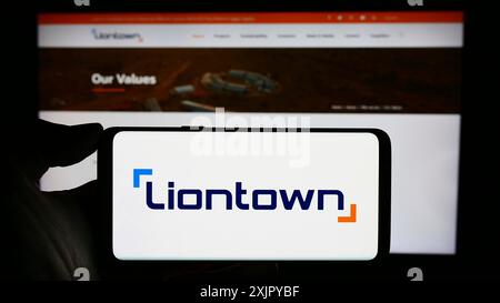 Stuttgart, 29.10.2023: Person, die ein Mobiltelefon mit dem Logo des australischen Bergbauunternehmens Liontown Resources Limited vor dem Unternehmen hält Stockfoto