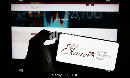 Stuttgart, 29.10.2023: Person, die ein Mobiltelefon mit dem Logo des australischen Unternehmens Elanor Commercial Property Fund vor der Geschäftsstelle hält Stockfoto