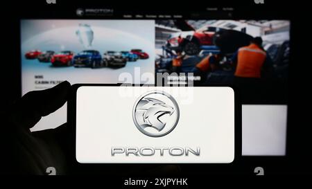 Stuttgart, Deutschland, 10-31-2023: Person, die ein Smartphone mit dem Logo des malaysischen Automobilkonzerns Proton Holdings Berhad (PHB) vor der Website hält. Stockfoto