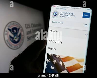 Stuttgart, 29.10.2023: Person, die ein Smartphone mit Website der US-amerikanischen Behörde Citizenship and Immigration Services (USCIS) mit Siegel hält. Konzentrieren Sie sich auf Stockfoto