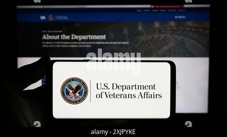 Stuttgart, Deutschland, 10-30-2023: Person, die ein Smartphone mit dem Siegel des United States Department of Veterans Affairs (VA) vor der Website hält. Fokus Stockfoto