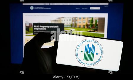 Stuttgart, Deutschland, 10-30-2023: Person mit Handy mit Logo des amerikanischen Ministeriums für Wohnungsbau und Stadtentwicklung (HUD) vor der Webseite. Stockfoto