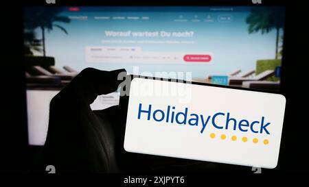 Stuttgart, Deutschland, 11.02.2023: Handybesitzer mit Logo des Schweizer Reisebuchungsportals HolidayCheck AG vor der Webseite. Stockfoto