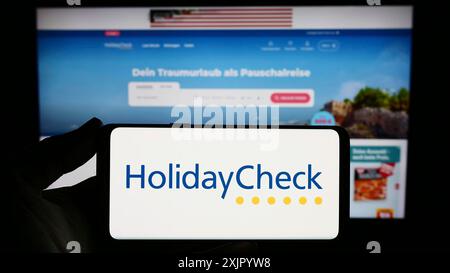 Stuttgart, Deutschland, 11.02.2023: Person mit Smartphone mit Logo des Schweizer Reisebuchungsportals HolidayCheck AG vor der Website. Fokus Stockfoto