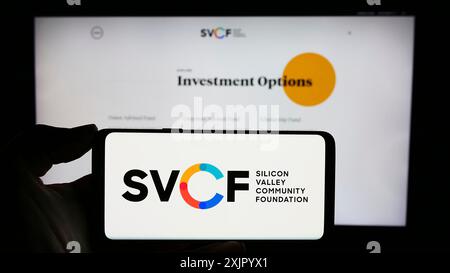 Stuttgart, Deutschland, 11.02.2023: Person mit Handy mit Logo der US-Organisation Silicon Valley Community Foundation (SVCF) vor der Webseite. Stockfoto