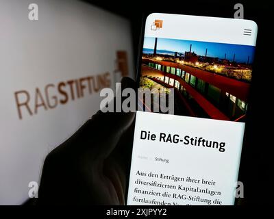 Stuttgart, 11.02.2023: Handybesitzer mit Website der RAG-Stiftung vor Logo. Konzentrieren Sie sich auf die Mitte des Telefons Stockfoto