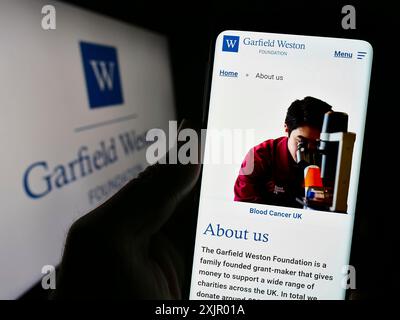 Stuttgart, Deutschland, 11.03.2023: Person, die ein Mobiltelefon mit Webseite der britischen Wohltätigkeitsorganisation Garfield Weston Foundation mit Logo hält. Fokus Stockfoto