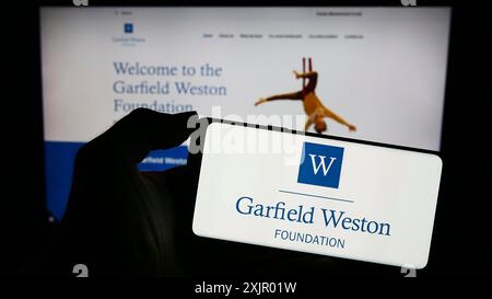 Stuttgart, Deutschland, 11.03.2023: Person mit Handy mit Logo der britischen Wohltätigkeitsorganisation Garfield Weston Foundation vor der Webseite. Stockfoto