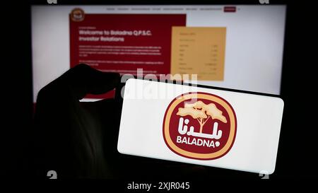 Stuttgart, Deutschland, 11.03.2023: Person mit Handy mit Logo des katarischen Molkerei- und Lebensmittelunternehmens Baladna vor der Business-Website. Konzentrieren Sie sich auf Stockfoto