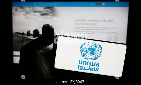 Stuttgart, Deutschland, 11.03.2023: Person, die ein Smartphone mit dem Logo des United Nations Plalestine Flüchtlingshilfswerks UNRWA vor der Website hält. Konzentrieren Sie sich auf Stockfoto