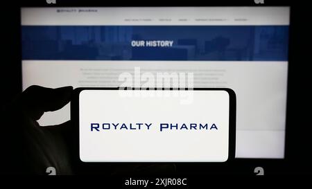 Stuttgart, Deutschland, 11.07.2023: Person, die ein Mobiltelefon mit dem Logo des US-amerikanischen biopharmazeutischen Lizenzunternehmens Royalty Pharma vor dem Geschäft hält Stockfoto