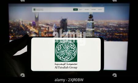 Stuttgart, Deutschland, 11.06.2023: Person, die ein Smartphone mit dem Logo des Saudi-arabischen Unternehmens Al Faisaliah Group vor der Website hält. Konzentrieren Sie sich auf das Telefon Stockfoto