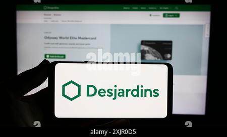 Stuttgart, Deutschland, 11.07.2023: Person mit Smartphone mit Logo des kanadischen Finanzdienstleistungsunternehmens Desjardins Group vor der Website. Stockfoto