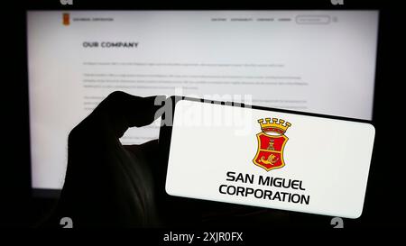 Stuttgart, Deutschland, 11.08.2023: Person mit Smartphone mit Logo der philippinischen Firma San Miguel Corporation (SMC) vor der Website. Konzentrieren Sie sich auf Stockfoto