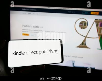 Stuttgart, Deutschland, 11.09.2023: Person mit Mobiltelefon mit Logo der Amazon E-Book-Plattform Kindle Direct Publishing (KDP) vor dem Unternehmen Stockfoto