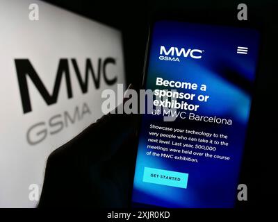 Stuttgart, Deutschland, 11.09.2023: Person mit Mobiltelefon mit Website der jährlichen Mobilfunkmesse MWC Barcelona vor dem Logo. Stockfoto