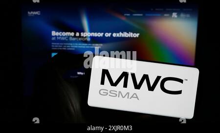 Stuttgart, Deutschland, 11.09.2023: Person, die ein Mobiltelefon mit Logo der jährlichen Mobilfunkmesse MWC Barcelona vor der Geschäftsstelle hält Stockfoto