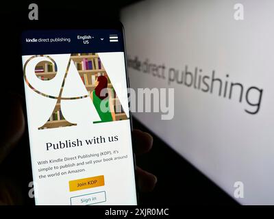 Stuttgart, Deutschland, 11.09.2023: Person, die ein Smartphone mit Webseite der Amazon E-Book-Plattform Kindle Direct Publishing (KDP) mit Logo hält. Konzentrieren Sie sich auf Stockfoto