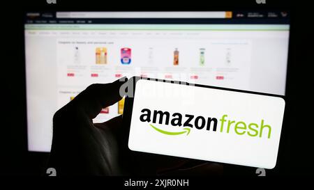 Stuttgart, Deutschland, 11.09.2023: Person mit Mobiltelefon mit Logo des amerikanischen Lebensmitteleinzelhandelsunternehmens Amazon Fresh vor der Business-Webseite. Stockfoto