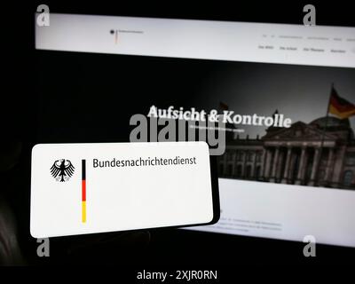 Stuttgart, 11.11.2023: Person mit Handy mit Logo des Bundesnachrichtendienstes (BND) vor der Webseite. Stockfoto