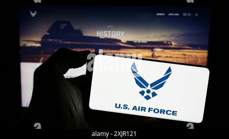 Stuttgart, Deutschland, 11.12.2023: Person, die ein Mobiltelefon mit dem Logo der United States Air Force (USAF) vor der Webseite hält. Schwerpunkt auf dem Display des Telefons Stockfoto