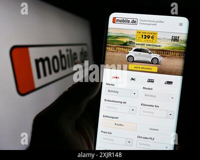 Stuttgart, 14.11.2023: Person mit Smartphone und Website der deutschen Auto-Online-Marketplace-Firma mobile.de GmbH vor dem Logo. Stockfoto