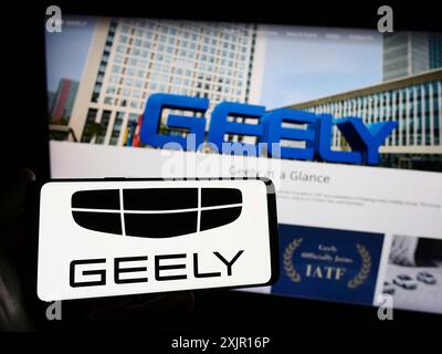 Stuttgart, 16.11.2023: Person, die ein Smartphone mit dem Logo des chinesischen Autoherstellers Zhejiang Geely Holding Group vor der Website hält. Stockfoto