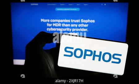 Stuttgart, 15.11.2023: Person, die ein Mobiltelefon mit Logo des britischen Sicherheitssoftware-Unternehmens Sophos Group plc vor der Geschäftsstelle hält Stockfoto