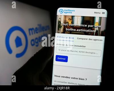 Stuttgart, 15.11.2023: Person, die ein Mobiltelefon hält, mit Webseite des französischen Immobilienplattformunternehmens MeilleursAgents vor dem Logo. Fokus Stockfoto