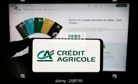 Stuttgart, Deutschland, 16. 11. 2023: Person mit Mobiltelefon mit Logo des französischen Finanzdienstleistungsunternehmens Credit Agricole SA vor Geschäftssitz Stockfoto