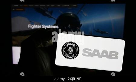 Stuttgart, 16.11.2023: Person mit Smartphone mit Logo des schwedischen Luft- und Raumfahrtunternehmens Saab ab ab vor der Website. Konzentrieren Sie sich auf Stockfoto