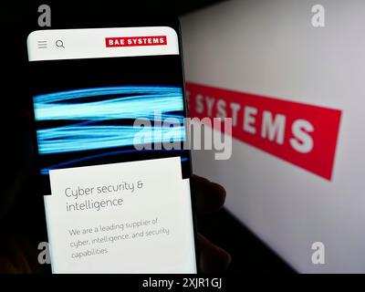 Stuttgart, 21.11.2023: Person, die ein Mobiltelefon hält, mit Webseite des britischen Luft- und Raumfahrt- und Verteidigungsunternehmens BAE Systems plc vor dem Logo. Stockfoto