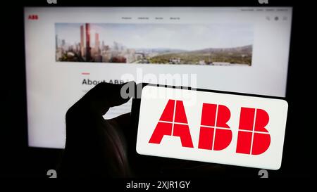 Stuttgart, 16.11.2023: Person, die ein Smartphone mit dem Logo des Elektrogeräteunternehmens ABB Ltd. Vor der Website hält. Konzentrieren Sie sich auf das Telefon Stockfoto
