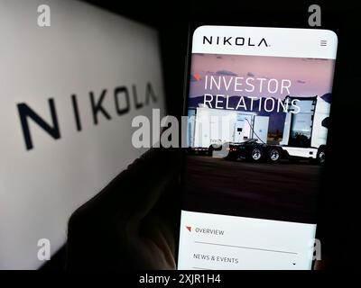 Stuttgart, 17.11.2023: Person, die ein Mobiltelefon hält, mit Webseite des US-amerikanischen Elektrofahrzeugunternehmens Nikola Corporation vor dem Logo. Konzentrieren Sie sich auf Stockfoto