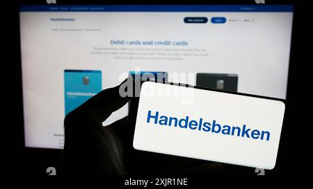 Stuttgart, 22.11.2023: Person mit Smartphone und Logo des schwedischen Finanzunternehmens Svenska Handelsbanken ab vor der Website. Fokus Stockfoto