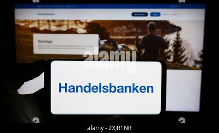 Stuttgart, Deutschland, 22.11.2023: Person, die ein Mobiltelefon mit Logo der schwedischen Finanzgesellschaft Svenska Handelsbanken ab vor der Geschäftsstelle hält Stockfoto