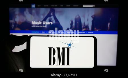 Stuttgart, 29.11.2023: Person, die ein Mobiltelefon mit Logo der amerikanischen Aufführungsrechtefirma Broadcast Music Inc. (BMI) hält Stockfoto