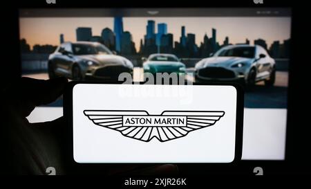 Stuttgart, Deutschland, 12.02.2023: Person, die ein Mobiltelefon mit dem Logo des britischen Unternehmens Aston Martin Lagonda Global Holdings plc vor der Webseite hält. Stockfoto