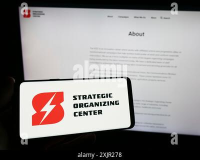 Stuttgart, 29.11.2023: Person mit Smartphone mit Logo der gewerkschaftskoalition Strategic Organizing Center (SOC) vor der Website. Stockfoto