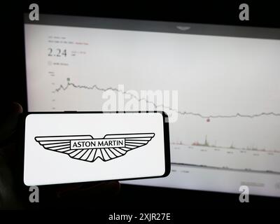 Stuttgart, Deutschland, 12.02.2023: Person, die ein Mobiltelefon mit dem Logo des britischen Unternehmens Aston Martin Lagonda Global Holdings plc vor dem Internet hält Stockfoto