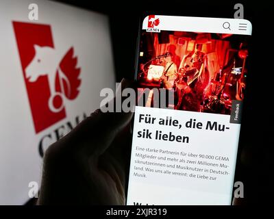 Stuttgart, 14.12.2023: Person mit Smartphone mit Webseite der deutschen Verwertungsgesellschaft GEMA vor Logo. Konzentrieren Sie sich auf die Mitte des Telefons Stockfoto