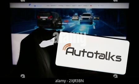 Stuttgart, Deutschland, 18.12.2023: Person, die ein Mobiltelefon mit dem Logo des israelischen Automobilhersteller Autotalks Ltd. Vor dem Geschäft hält Stockfoto