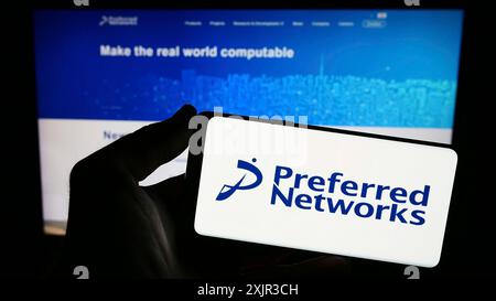 Stuttgart, 18.12.2023: Person, die ein Smartphone mit dem Logo des Künstlichen Intelligenz-Unternehmens Preferred Networks Inc. Vor der Website hält. Stockfoto