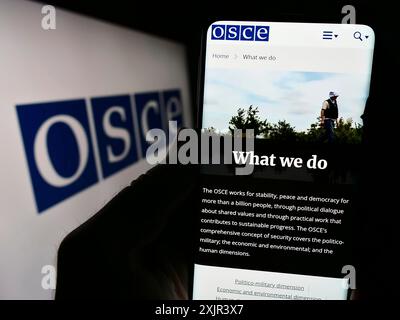 Stuttgart, Deutschland, 28.12.2023: Person, die ein Smartphone hält, mit Webseite der Organisation für Sicherheit und Zusammenarbeit in Europa (OSZE) mit Logo. Stockfoto