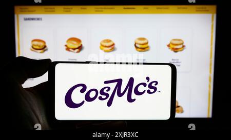 Stuttgart, 28.12.2023: Person, die ein Mobiltelefon mit dem Logo der US-amerikanischen Fastfood-Kette CosMc's (McDonalds) vor der Webseite hält. Stockfoto