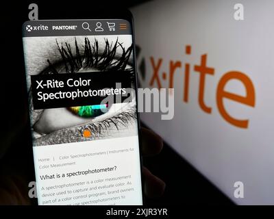 Stuttgart, Deutschland, 28.12.2023: Person, die ein Mobiltelefon hält, mit Webseite der US-amerikanischen Farbprodukte X-Rite Inc. Vor dem Firmenlogo. Konzentrieren Sie sich auf die Mitte Stockfoto