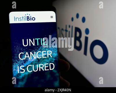 Stuttgart, Deutschland, 12-31-2023: Person mit Smartphone und Webseite des US-Biotechnologie-Unternehmens Instil Bio Inc. Vor dem Firmenlogo. Fokus Stockfoto
