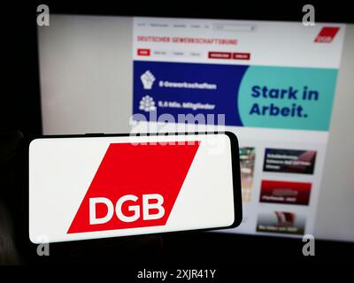 Stuttgart, 29.12.2023: Person mit Smartphone mit Logo des Deutschen Gewerkschaftsbundes (DGB) vor der Website. Stockfoto