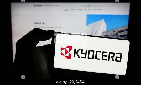 Stuttgart, Deutschland, 02-08-2024: Person, die ein Mobiltelefon mit dem Logo des japanischen Elektronikunternehmens Kyocera Corporation vor der Webseite hält. Stockfoto